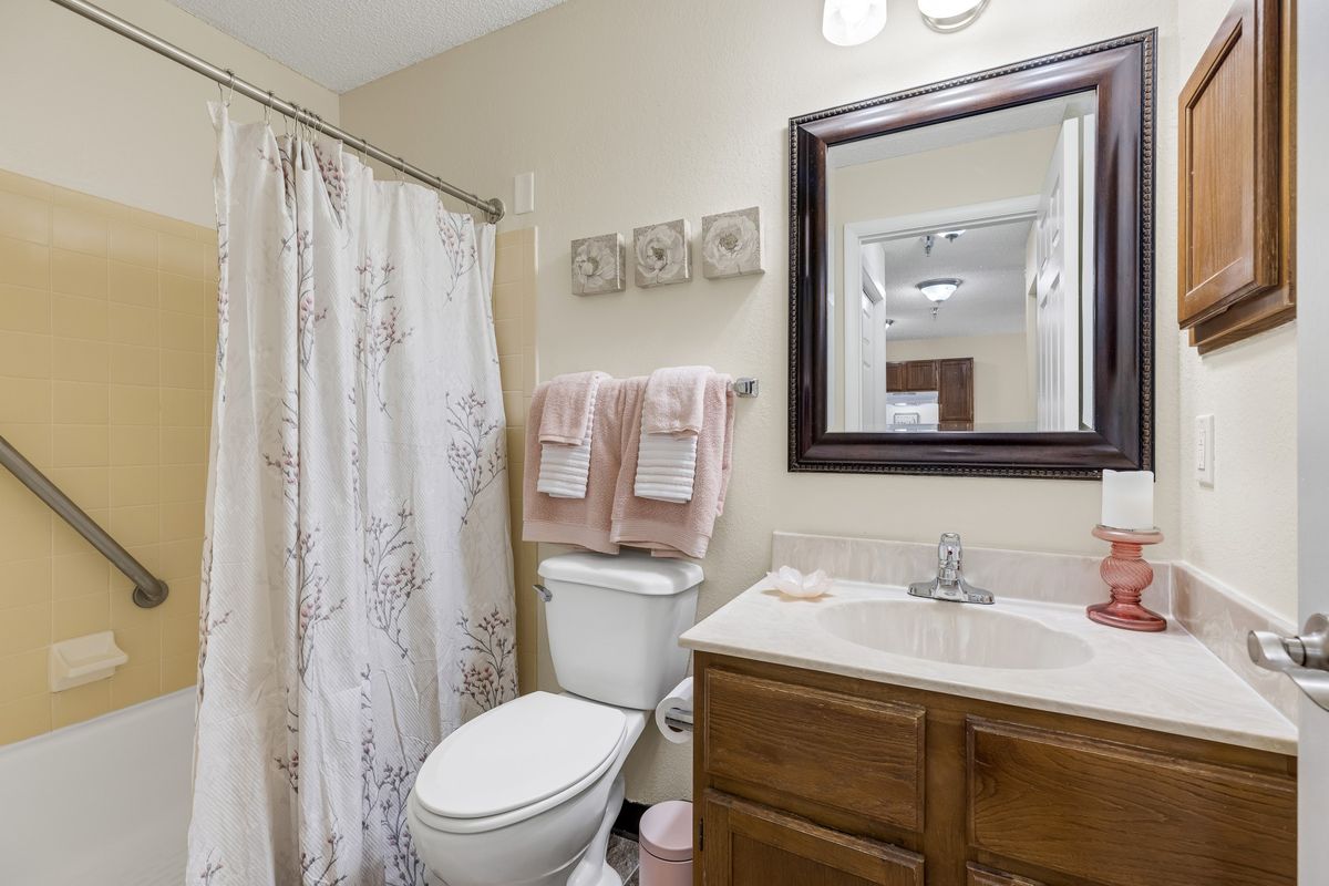 A neatly organized bathroom with a vanity mirror, shower curtain, and towels.
