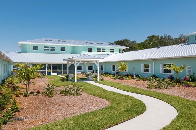 A modern residential building with a landscaped garden and pathway under a clear blue sky.