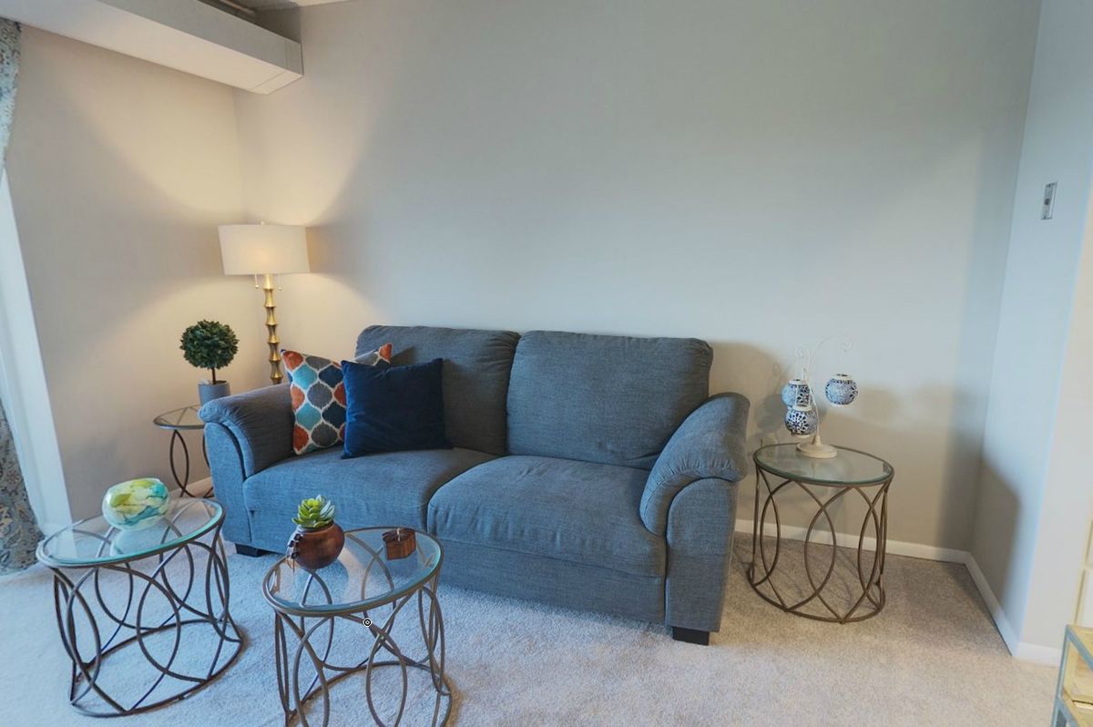A modern living room with a blue sofa, geometric side tables, and decorative cushions.