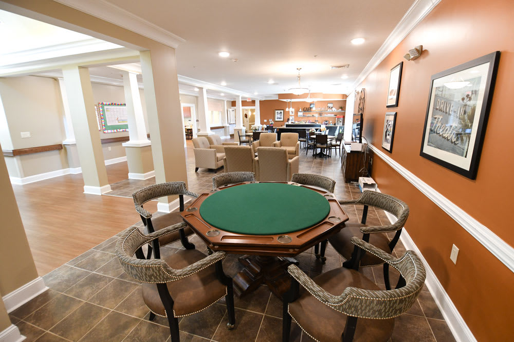 A spacious game room featuring a poker table surrounded by comfortable chairs.