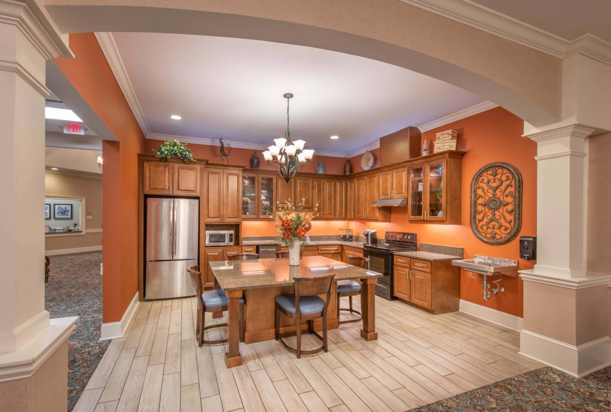 A warm and inviting kitchen with orange walls, wooden cabinets, and modern appliances.