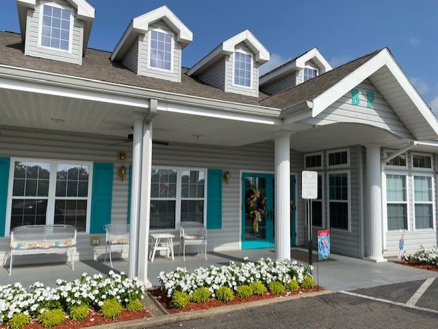 A charming house with a front porch and blooming flowers under a clear blue sky.
