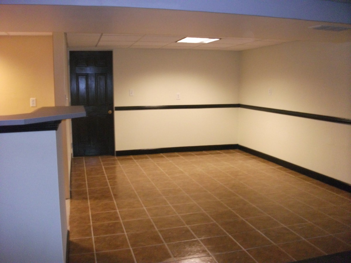 A vacant interior space featuring tiled flooring and a single door.