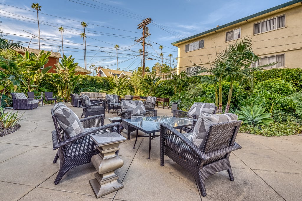 A cozy outdoor patio with comfortable seating and lush greenery.