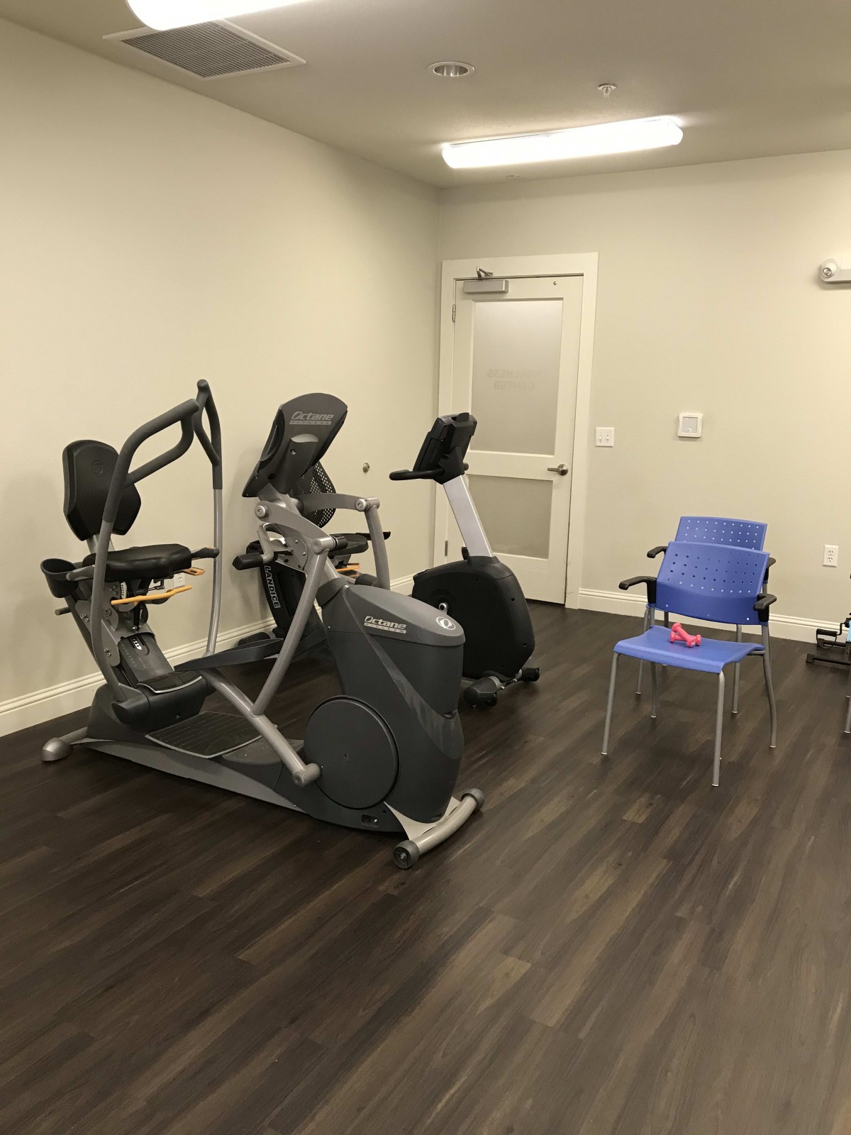 A small gym room featuring stationary exercise bikes and chairs.