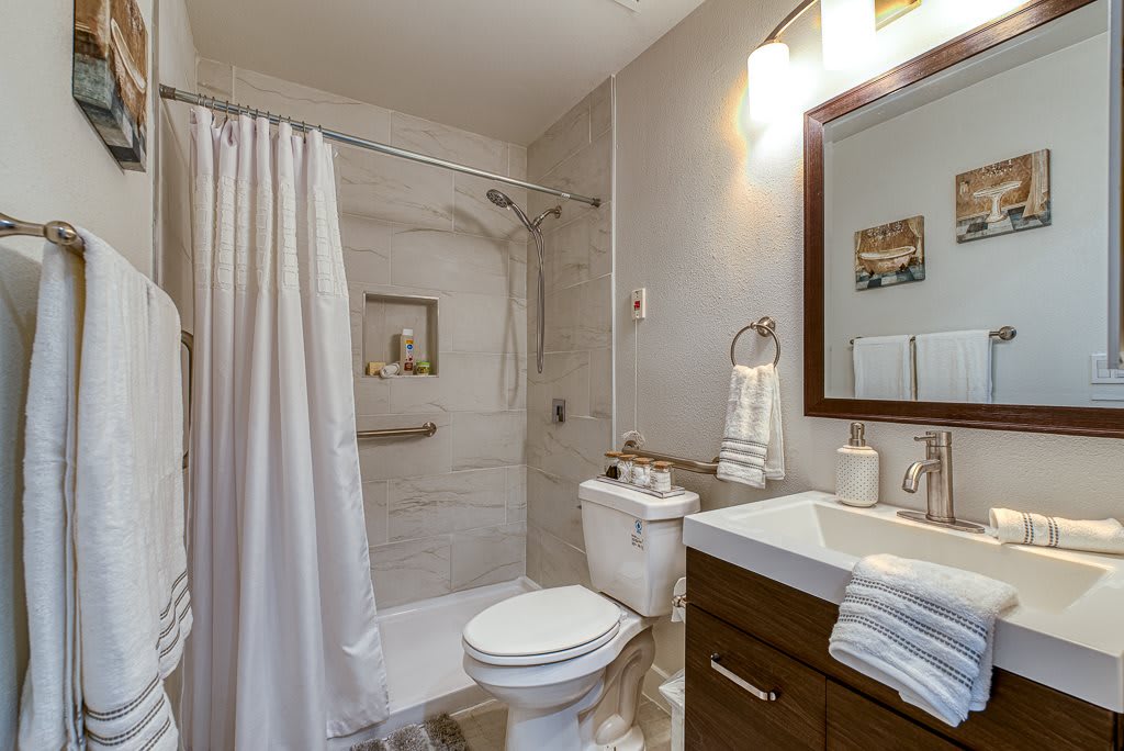 A modern bathroom with a shower, toilet, and sink.