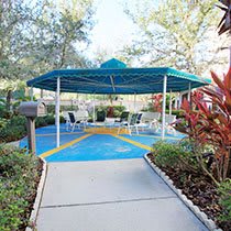 A shaded outdoor seating area surrounded by lush trees and plants.