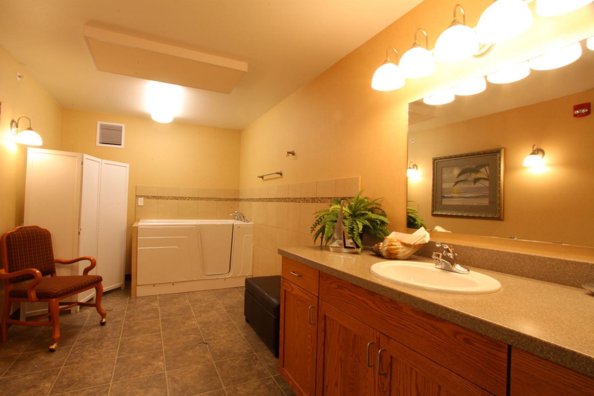 A well-lit bathroom with a sink, mirror, and integrated laundry area.