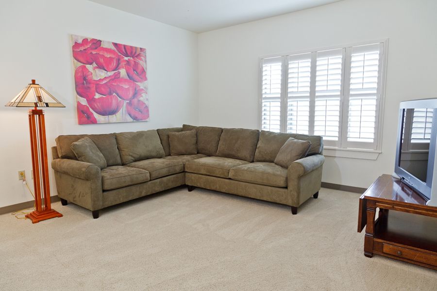 A cozy living room with a corner sofa and colorful wall art.