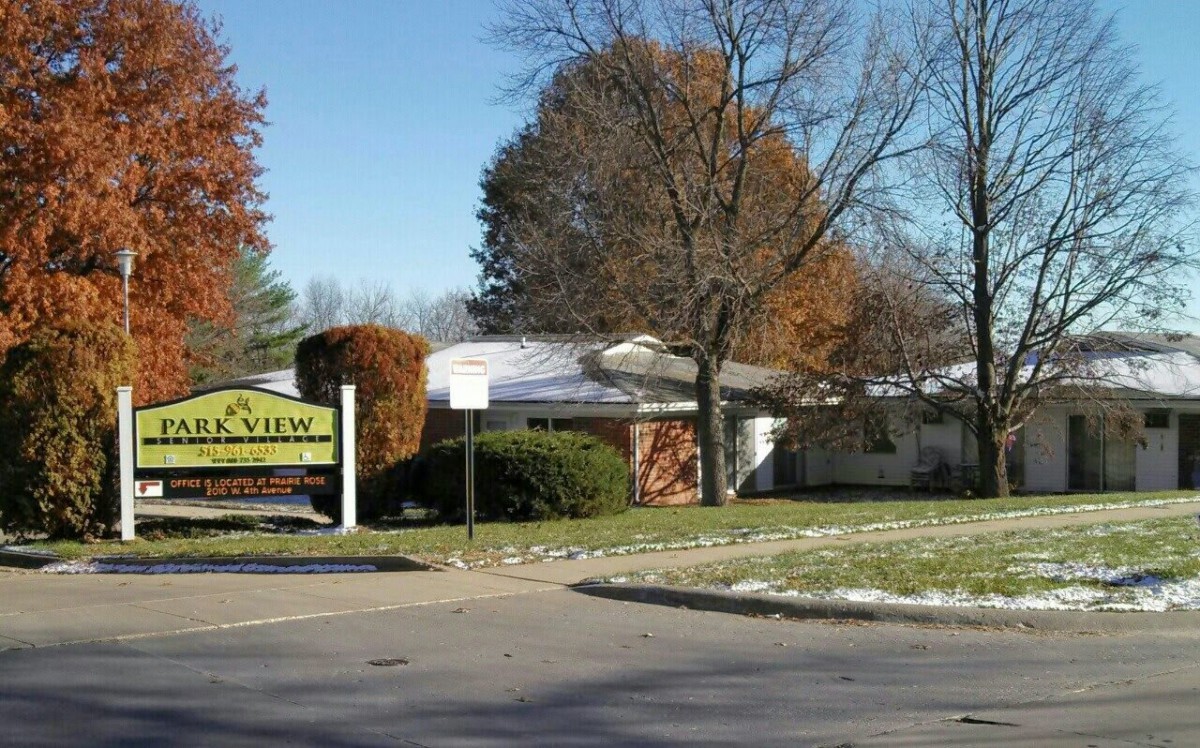 A real estate office surrounded by autumn trees with a sign in front.