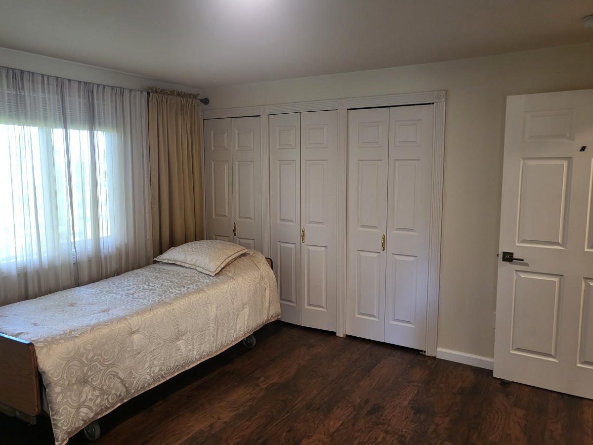A cozy bedroom with a single bed, large closet, and hardwood flooring.