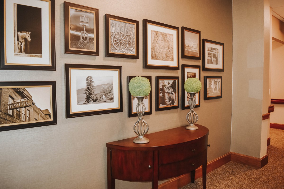 A decorated hallway featuring a series of framed photographs and a wooden console table adorned with decorative globes.