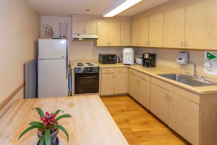 A modern kitchen with light wood cabinets and various appliances.