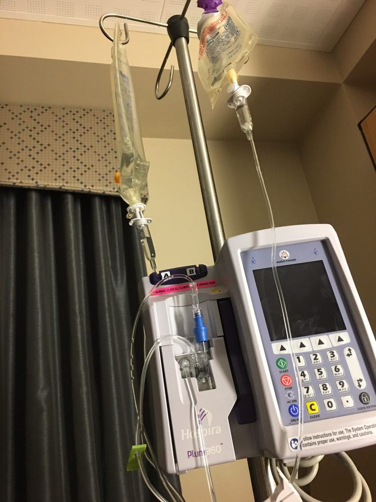 A hospital room showing an IV drip connected to a medical infusion pump.