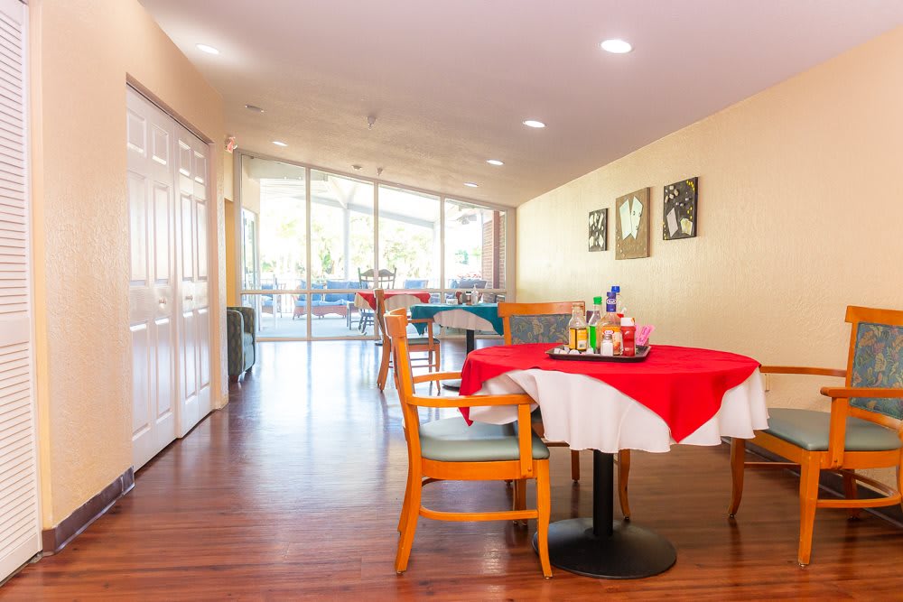 A modern dining area with bright lighting, featuring a table with chairs on a hardwood floor.