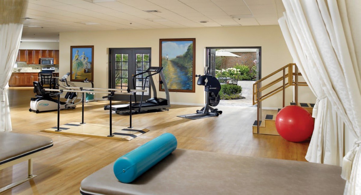A well-equipped gym with exercise machines and a yoga mat in a bright, open space.