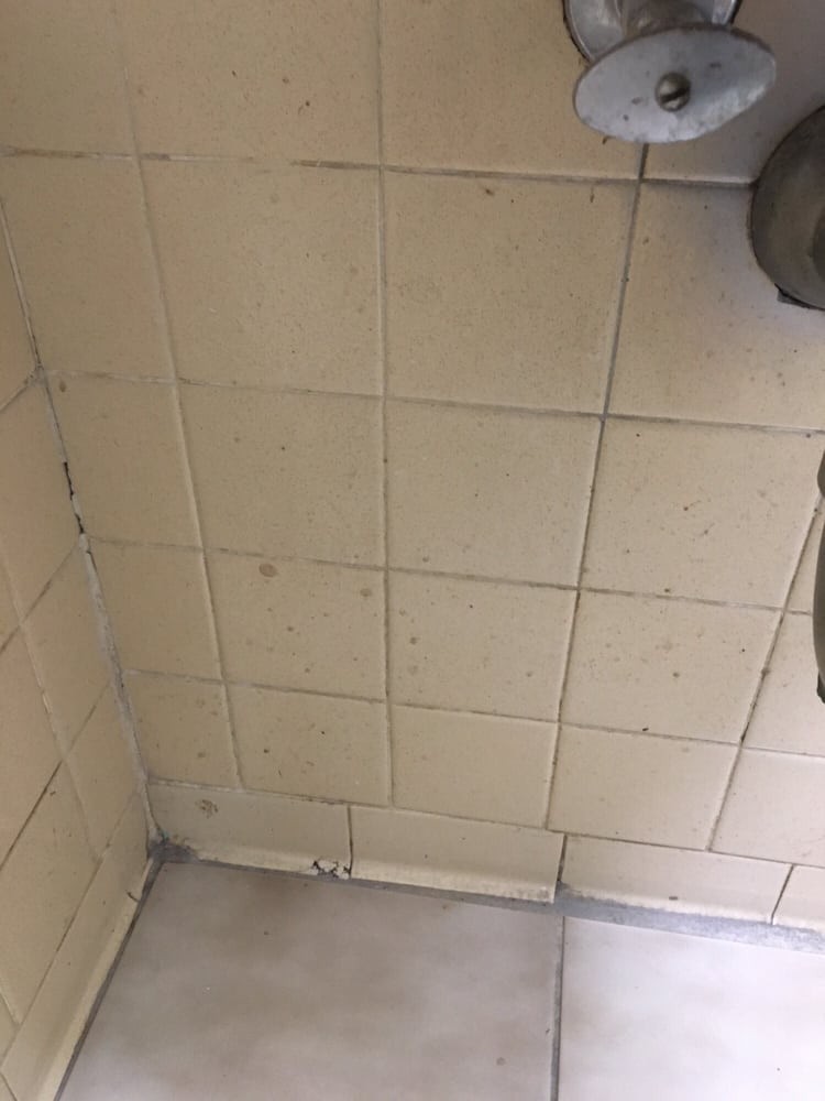 A bathroom corner with tiled walls and floor.