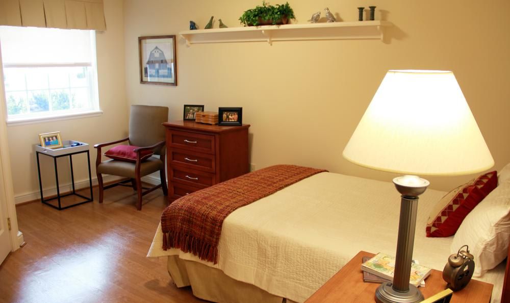 A cozy bedroom with a neatly made bed, wooden furniture, and soft lighting.