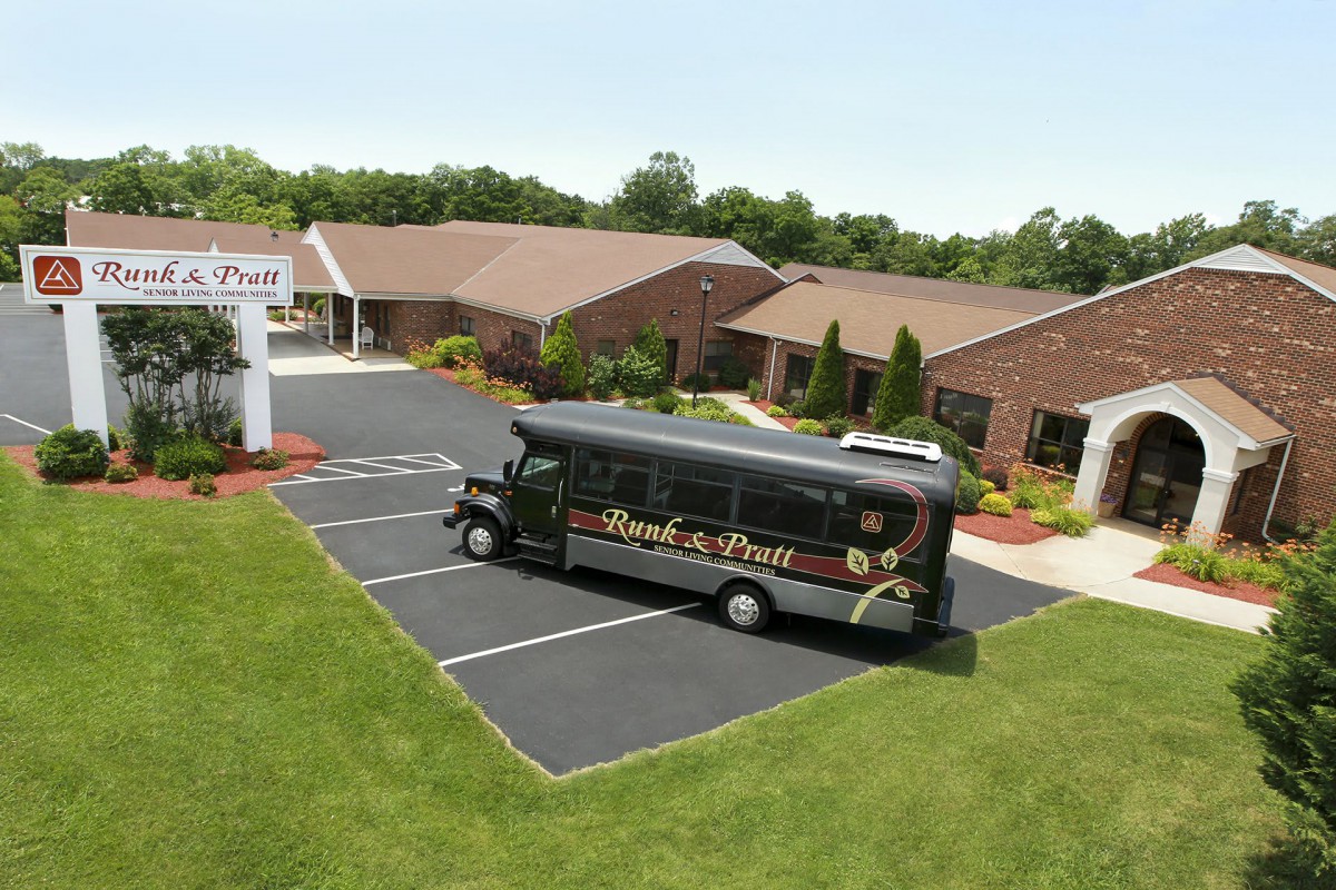 A black shuttle bus parked outside a brick building with a neatly maintained lawn.