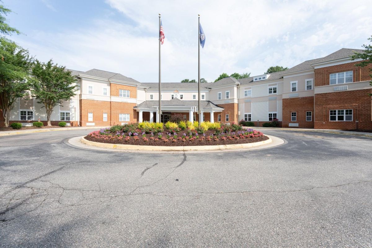 A large building with a circular driveway featuring landscaping and flags at the entrance.