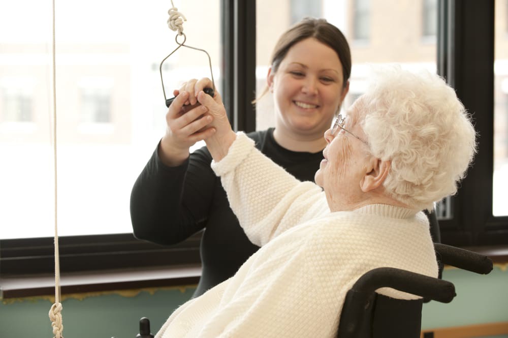A caregiver assists an elderly person, providing support and care in a nursing home setting.