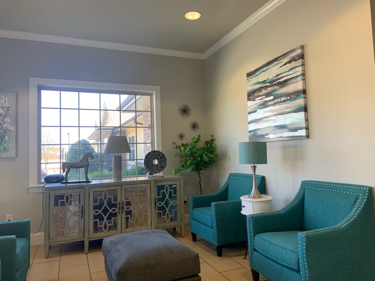 A cozy living room area featuring teal chairs, decorative lamps, and abstract wall art.