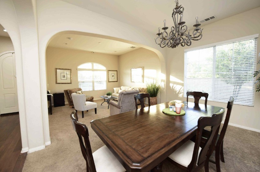A cozy dining and living area featuring a wooden table with chairs and a decorative chandelier.