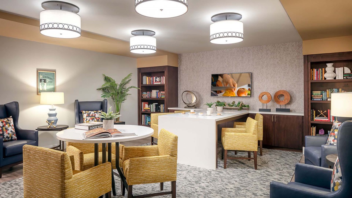 A modern living space featuring a dining area and bookshelf, with contemporary furniture and decor.