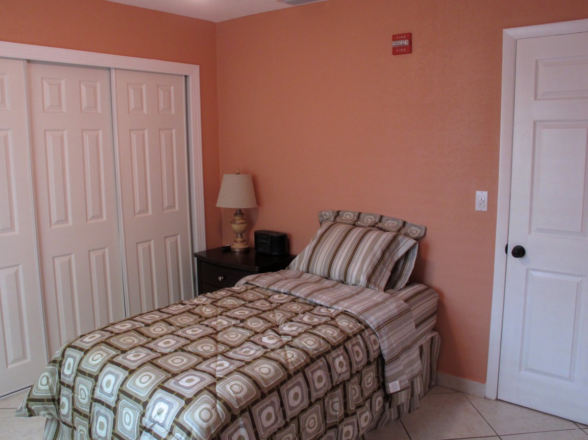 A cozy bedroom with a single bed, lamp, and closet.