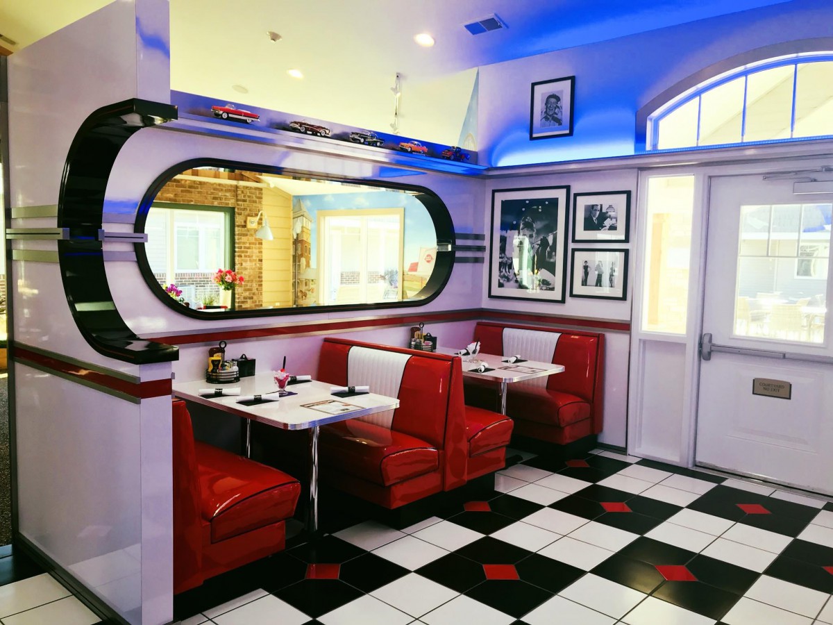 A retro-style diner with vibrant red booths and a classic checkerboard floor.