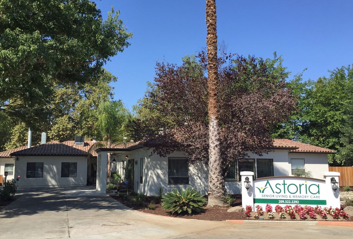 A residential building surrounded by trees with a sign in front.