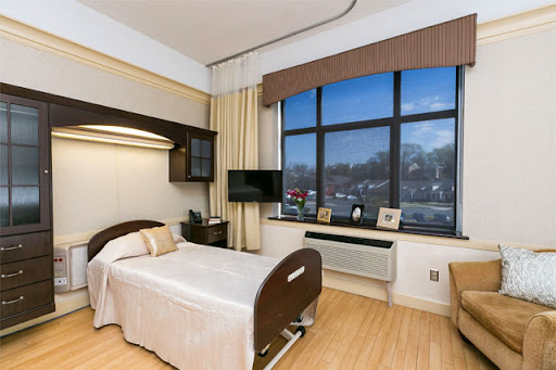 A well-lit, modern hospital patient room with a bed, television, and a view outside.