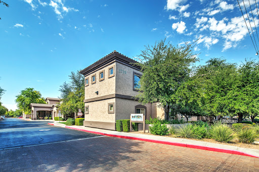 A modern building surrounded by greenery under a clear blue sky.