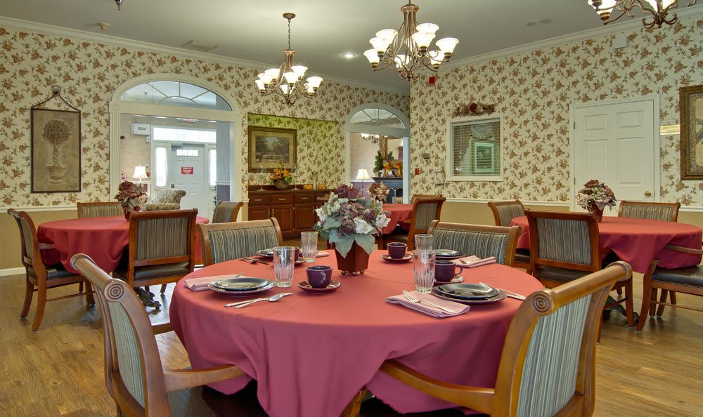 An elegantly set dining room with floral decorations and chandeliers.