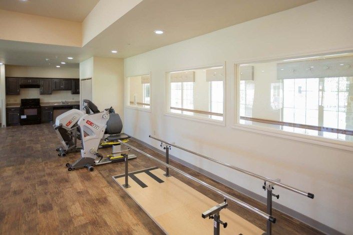 A well-lit gym room featuring exercise equipment including treadmills and mirrors.