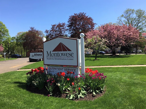 A welcoming sign surrounded by vibrant flowers and lush greenery in a spring setting.