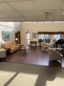 A spacious living room with comfortable seating, a grand piano, and large windows allowing natural light.