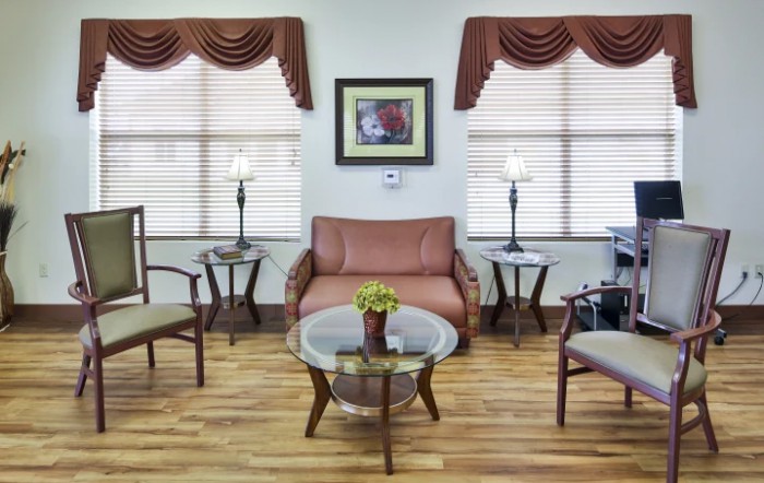 A cozy living room with a sofa, chairs, and a coffee table, complemented by stylish lamps and wood flooring.
