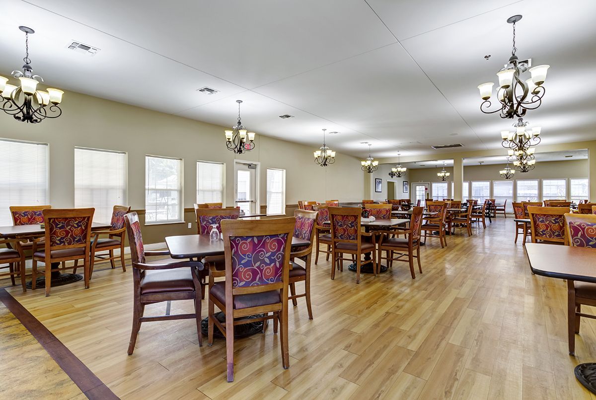 A spacious dining area with wooden floors and neatly arranged tables and chairs.