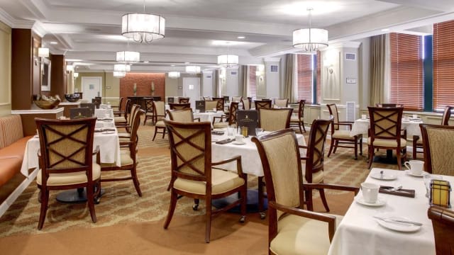 A spacious and elegant dining room with neatly arranged tables and chairs, featuring modern lighting fixtures.