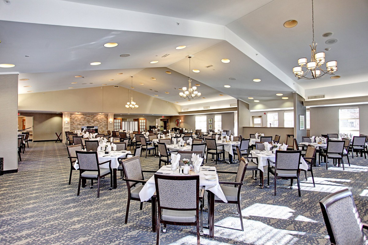 A spacious dining area with neatly arranged tables and chairs, featuring elegant chandeliers.