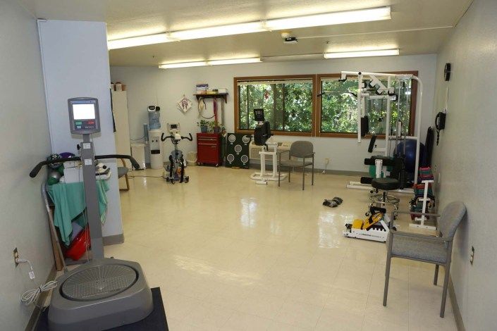 A physical therapy room equipped with various exercise machines and therapy tools.