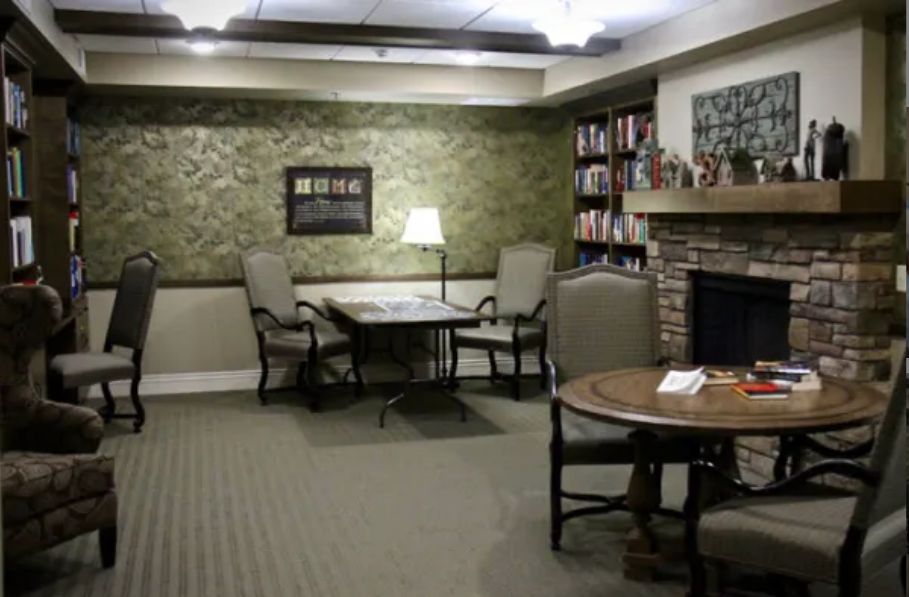 Cozy library corner with seating around a fireplace and bookshelves.