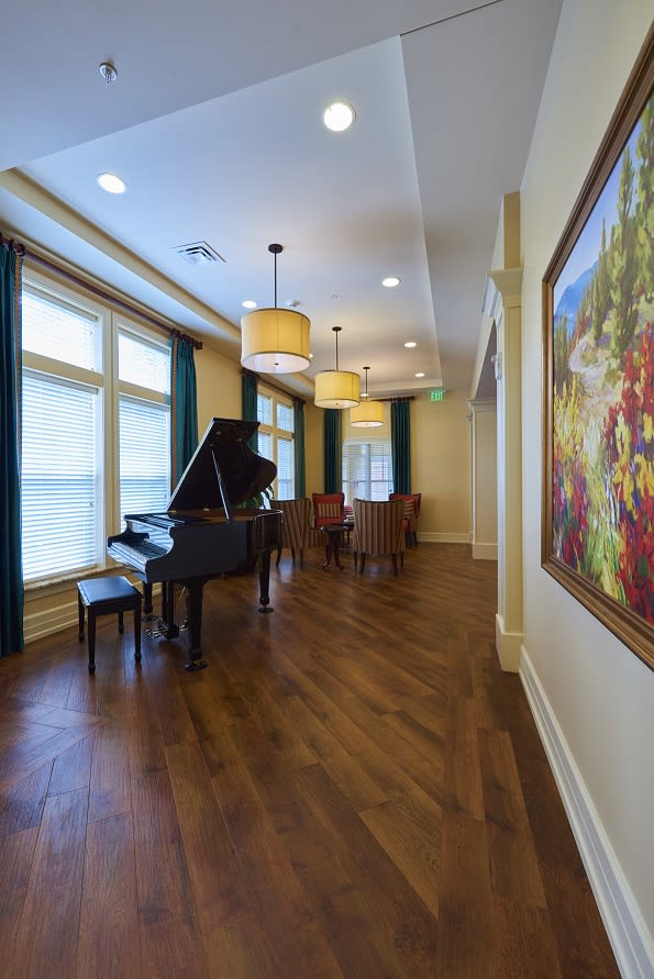 A spacious room featuring a grand piano with elegant decor and large windows.