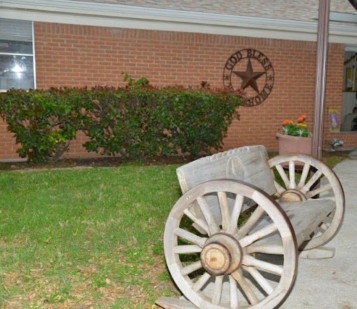 A rustic cannon on display in a garden, with a decorative star on the brick wall behind it.