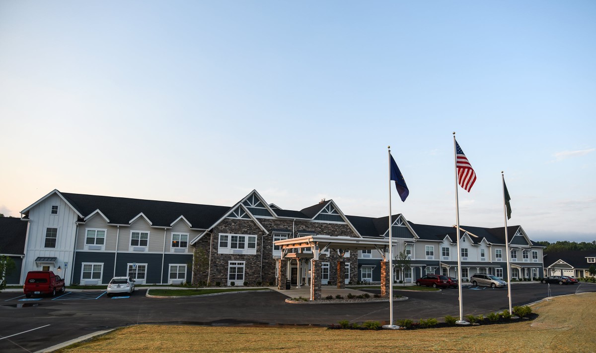 A large building with flags at the entrance against a clear sky.