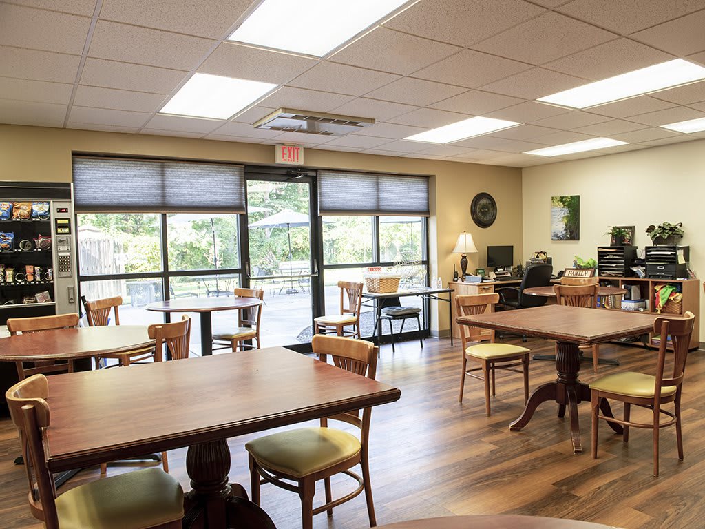 A cozy cafe interior with wooden tables and chairs, featuring large windows and a warm atmosphere.