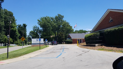 A clear day at a building with a parking lot and trees.