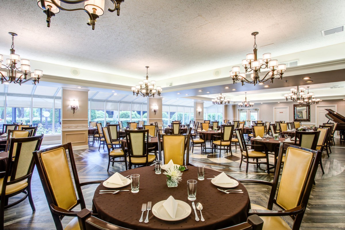 An elegant dining room with neatly arranged tables and chandeliers.