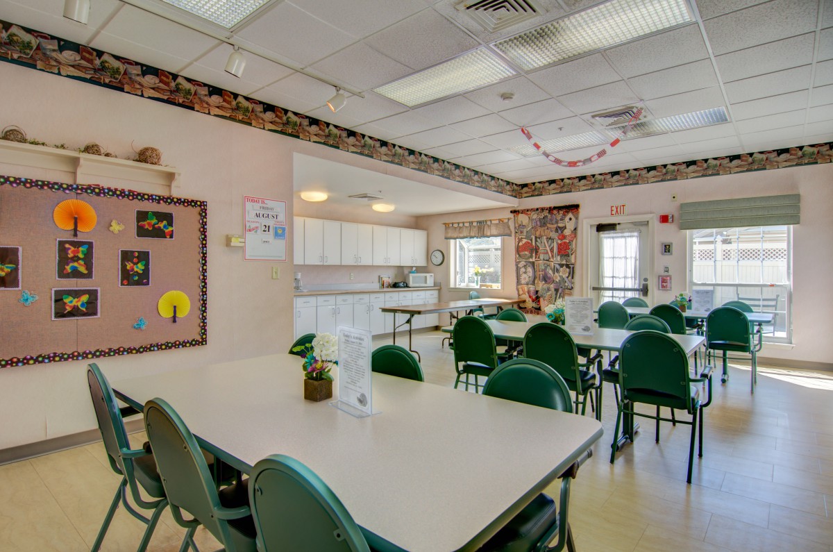 A classroom interior with tables, green chairs, and educational decorations.